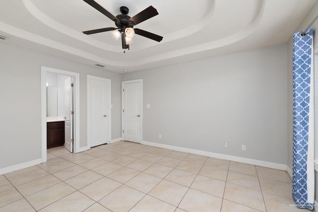 3222 Princess St, Edinburg, TX 78539 - unfurnished bedroom with a tray ceiling, ensuite bath, a ceiling fan, and baseboards