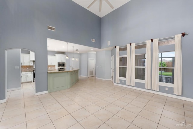 3222 Princess St, Edinburg, TX 78539 - unfurnished living room with a high ceiling, a ceiling fan, baseboards, arched walkways, and light tile patterned flooring