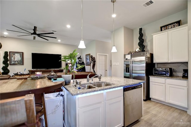 kitchen with sink, light stone counters, pendant lighting, white cabinets, and appliances with stainless steel finishes