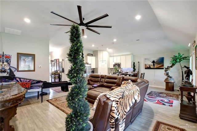 living room with ceiling fan, light hardwood / wood-style flooring, and lofted ceiling