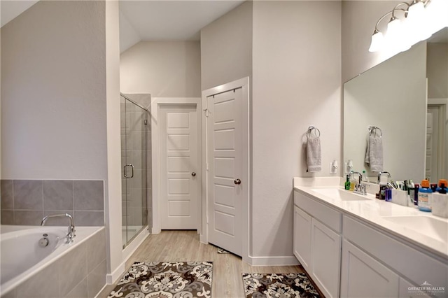 bathroom featuring independent shower and bath, vanity, wood-type flooring, and vaulted ceiling