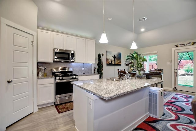 kitchen featuring backsplash, an island with sink, decorative light fixtures, white cabinets, and appliances with stainless steel finishes