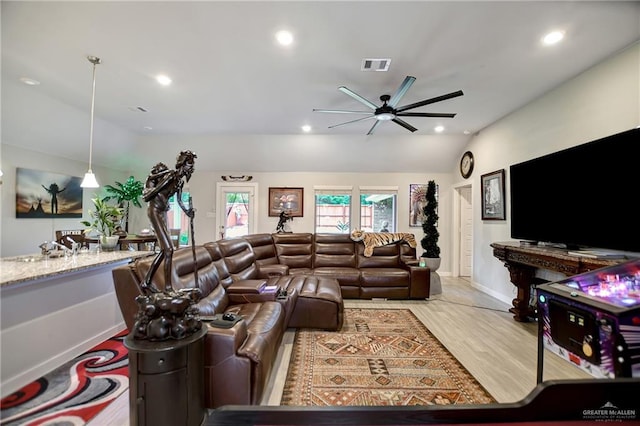 living room featuring ceiling fan, light hardwood / wood-style floors, and vaulted ceiling