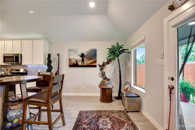 dining room with light hardwood / wood-style floors and vaulted ceiling