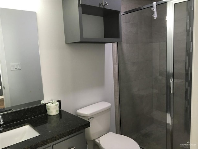 bathroom featuring vanity, toilet, and a shower with door