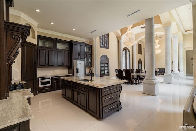 kitchen with appliances with stainless steel finishes, dark brown cabinetry, light tile patterned floors, and ornate columns