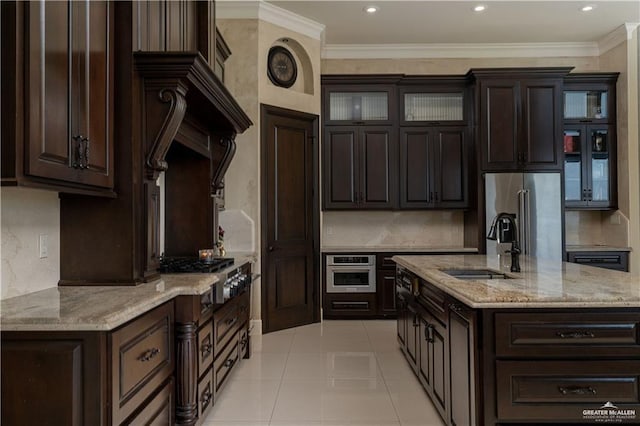 kitchen with appliances with stainless steel finishes, dark brown cabinetry, light tile patterned floors, and sink