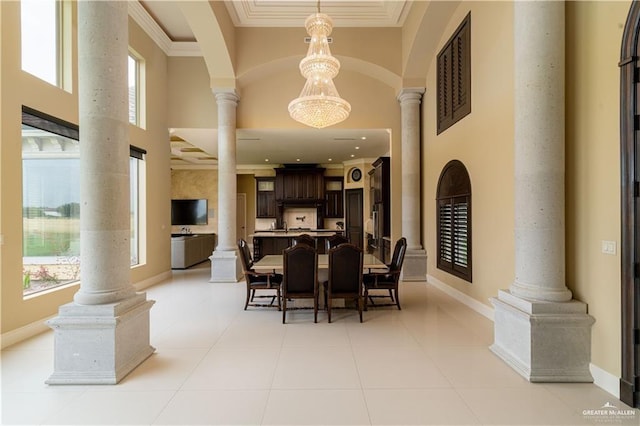 dining space with a towering ceiling, a chandelier, light tile patterned floors, and ornamental molding