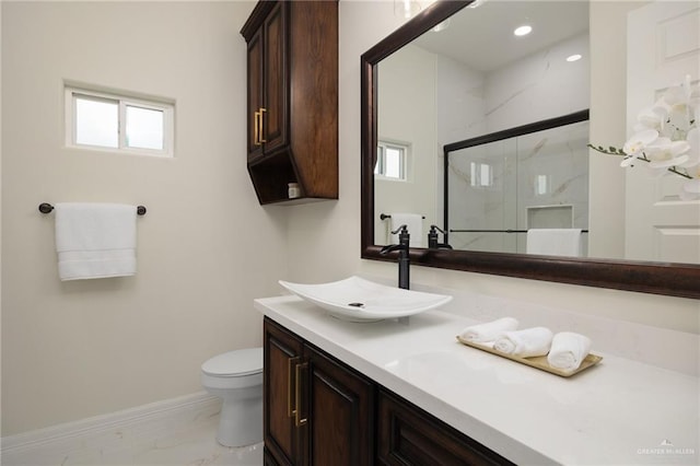 bathroom featuring vanity, toilet, and a shower with shower door