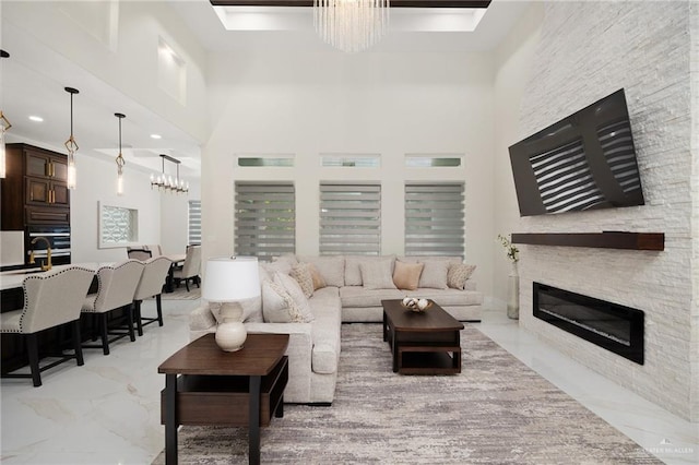 living room with a fireplace, a towering ceiling, and a notable chandelier