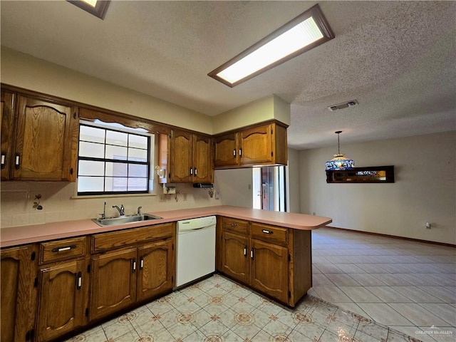 2028 Loker St, Mission, TX 78572 - kitchen with white dishwasher, a sink, a peninsula, a textured ceiling, and light countertops