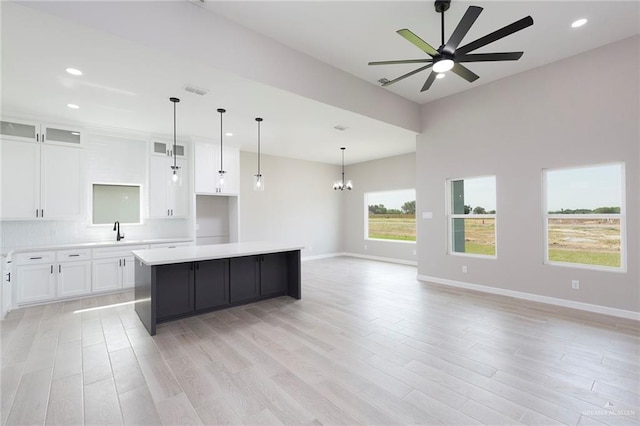 kitchen with a center island, white cabinets, ceiling fan with notable chandelier, decorative light fixtures, and light hardwood / wood-style floors