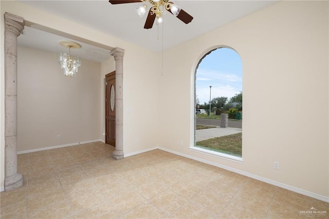 unfurnished room featuring decorative columns, light tile patterned floors, and ceiling fan with notable chandelier