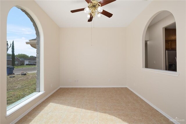 empty room featuring light tile patterned floors, plenty of natural light, and ceiling fan