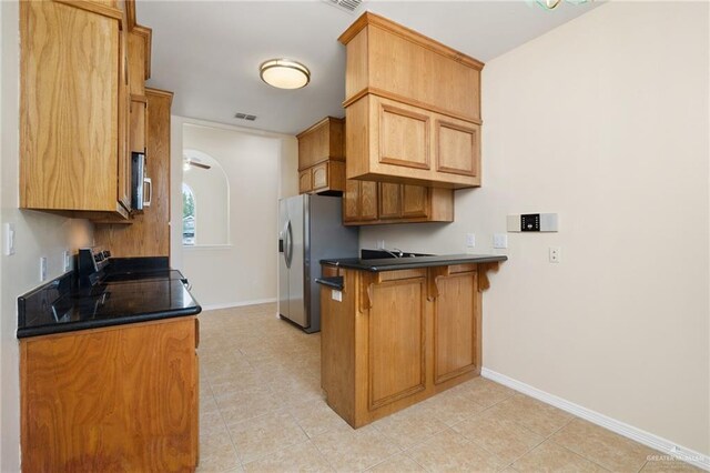 kitchen with ceiling fan, light tile patterned floors, a breakfast bar area, and appliances with stainless steel finishes