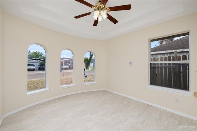 unfurnished room with ceiling fan, light hardwood / wood-style floors, and a raised ceiling