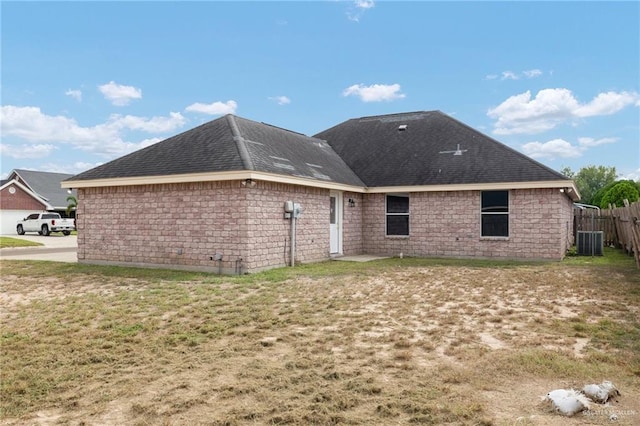 rear view of property featuring central AC and a lawn