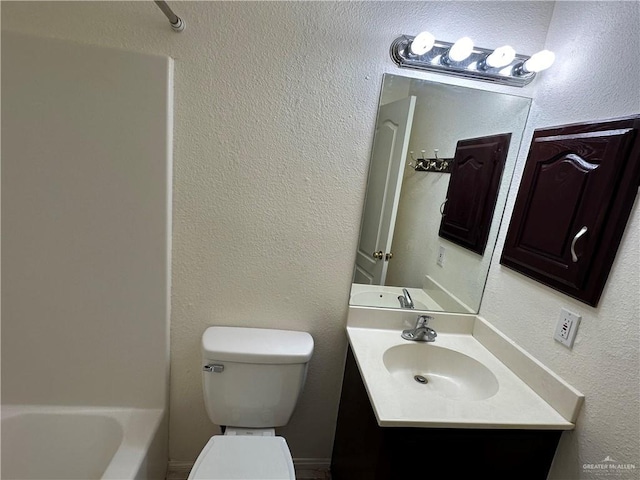 full bathroom with a textured wall, vanity, and toilet