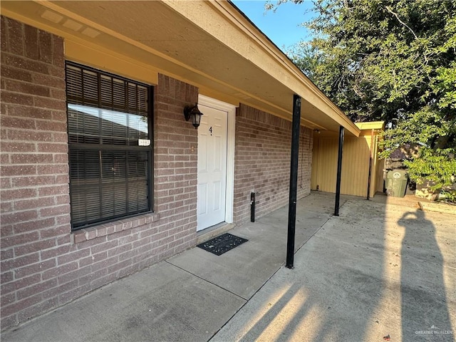 property entrance featuring a patio area and brick siding