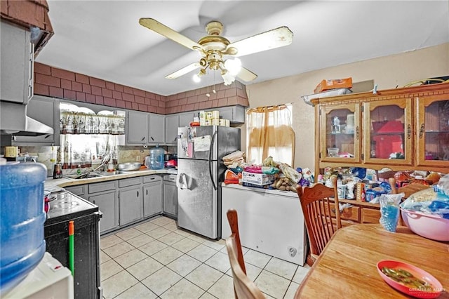 kitchen featuring stainless steel fridge, tasteful backsplash, ceiling fan, light tile patterned floors, and gray cabinets