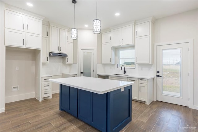 kitchen featuring pendant lighting, white cabinetry, sink, backsplash, and a center island