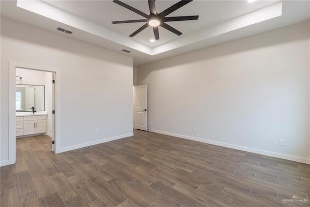 empty room featuring a raised ceiling and ceiling fan