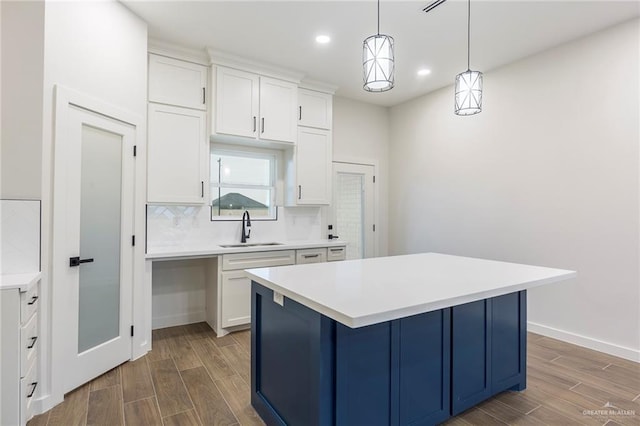 kitchen with sink, white cabinetry, a kitchen island, pendant lighting, and backsplash