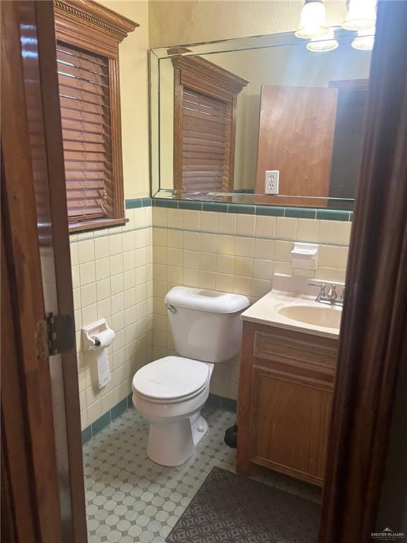 409 Redwood Ave, Mcallen, TX 78501 - half bathroom featuring tile walls, a wainscoted wall, toilet, vanity, and a chandelier