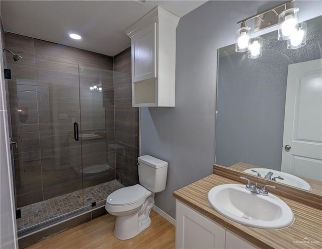 bathroom with hardwood / wood-style floors, vanity, toilet, and a shower with door