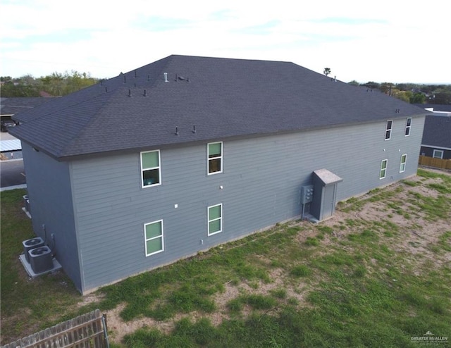 back of property with central air condition unit and a lawn