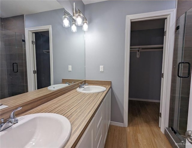 bathroom with wood-type flooring, vanity, an inviting chandelier, and a shower with door