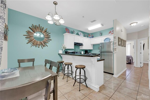 107 E Pike St Unit 2, South Padre Island, TX 78597 - kitchen featuring freestanding refrigerator, white cabinetry, light tile patterned floors, a peninsula, and dark countertops