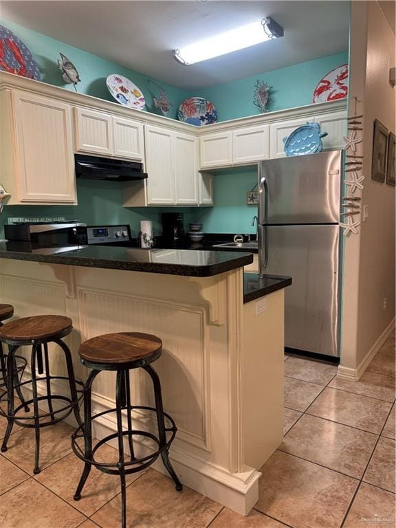 kitchen featuring light tile patterned floors, appliances with stainless steel finishes, exhaust hood, and a peninsula
