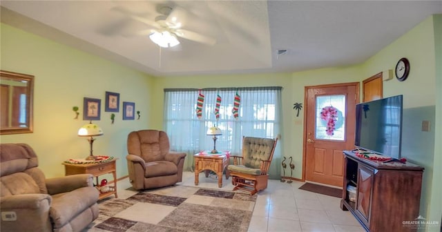 living room featuring light tile patterned floors, a raised ceiling, and ceiling fan