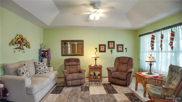 living room with a raised ceiling and ceiling fan