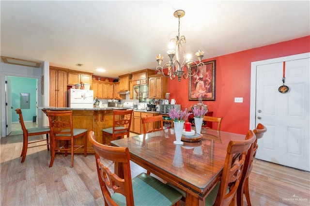 dining room with light wood-type flooring, electric panel, and a chandelier