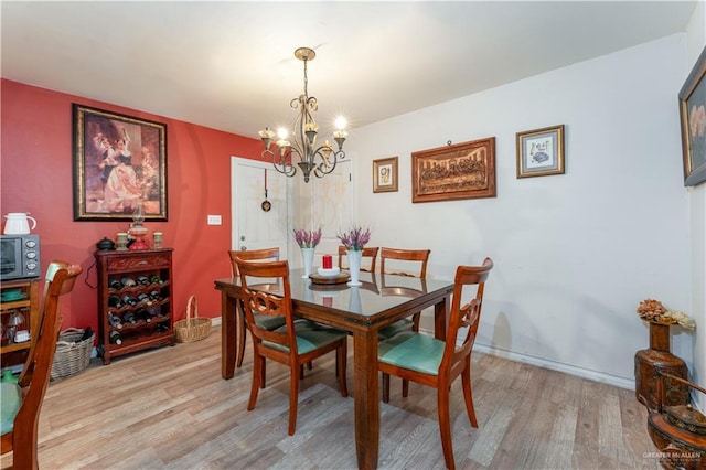 dining area featuring light wood-type flooring and a notable chandelier