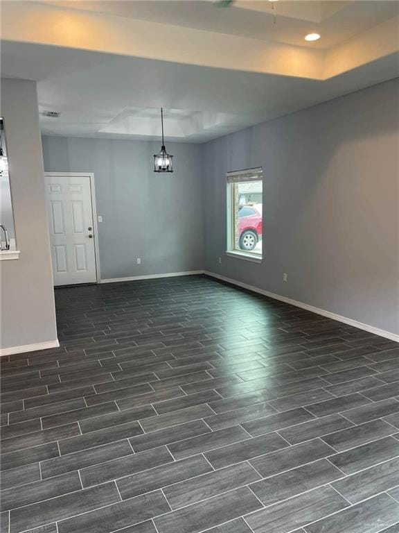 unfurnished room featuring a chandelier and a tray ceiling