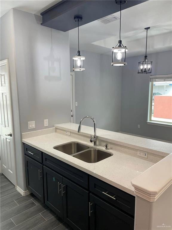 kitchen featuring pendant lighting, light stone counters, and sink