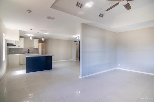 kitchen featuring white cabinets, a kitchen island, open floor plan, hanging light fixtures, and light countertops