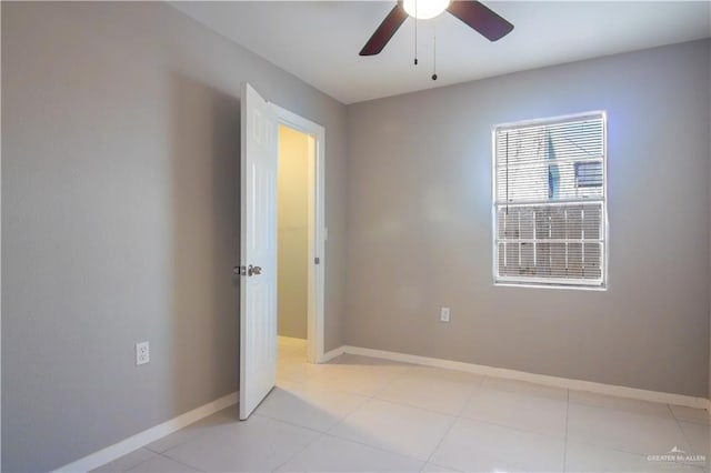 empty room featuring light tile patterned floors, baseboards, and a ceiling fan