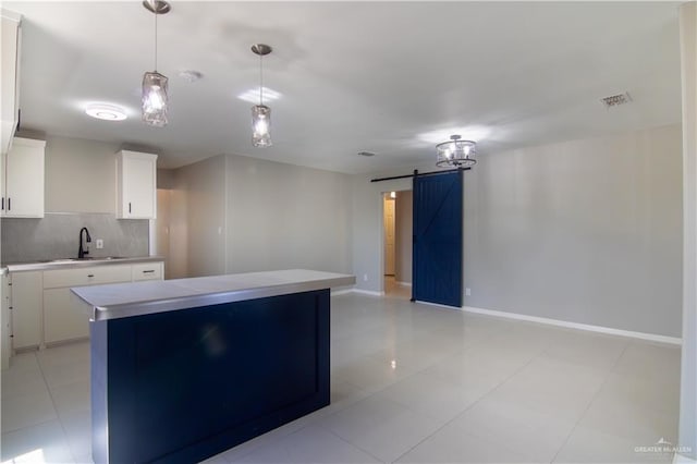 kitchen with a barn door, white cabinets, a center island, light countertops, and pendant lighting