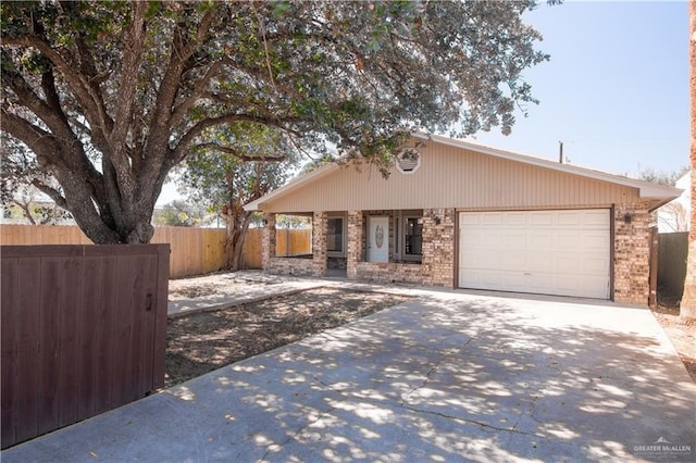 view of front of home featuring driveway, a garage, fence, and brick siding