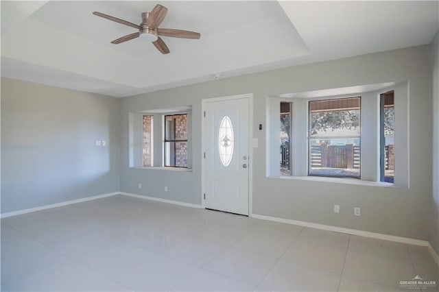 foyer entrance featuring a raised ceiling, a wealth of natural light, and baseboards