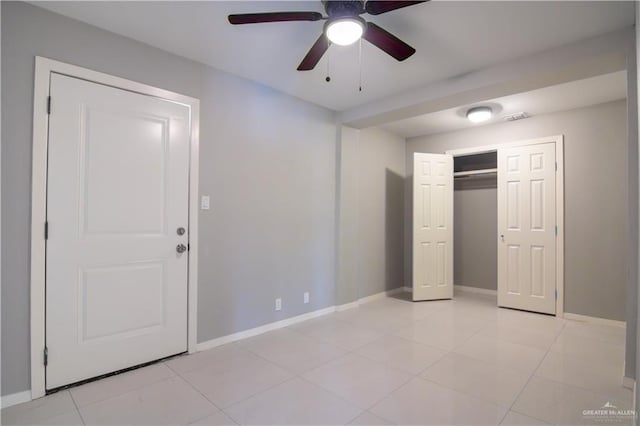 unfurnished bedroom featuring a closet, visible vents, a ceiling fan, light tile patterned flooring, and baseboards