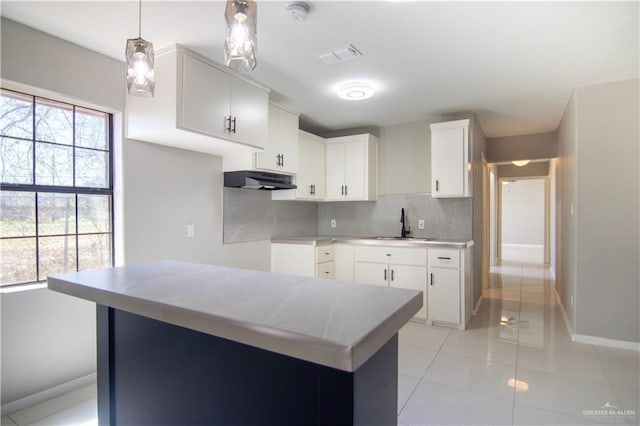 kitchen featuring decorative light fixtures, light countertops, visible vents, white cabinets, and under cabinet range hood