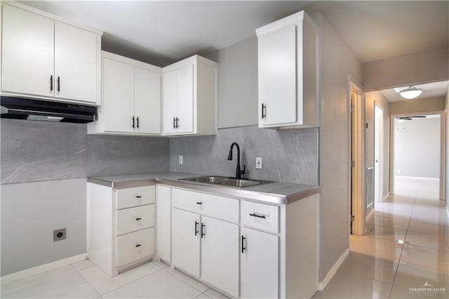 kitchen with decorative backsplash, light countertops, under cabinet range hood, white cabinetry, and a sink