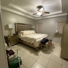 tiled bedroom with ceiling fan and a tray ceiling