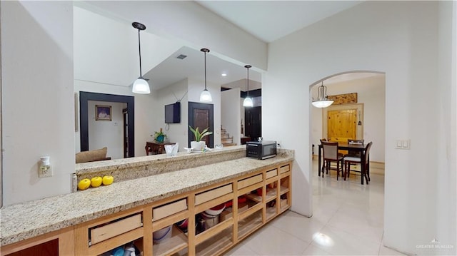 kitchen with light stone counters, light tile patterned flooring, and hanging light fixtures