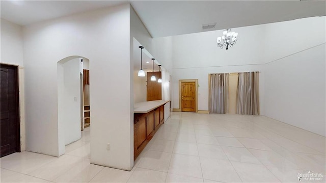 interior space with a chandelier, a high ceiling, and light tile patterned floors